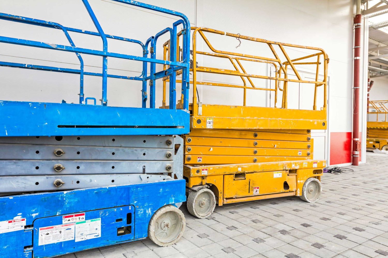 Two narrow aisle scissor lifts indoors on tile flooring